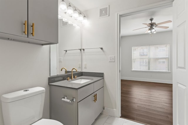 bathroom with visible vents, baseboards, toilet, vanity, and a ceiling fan