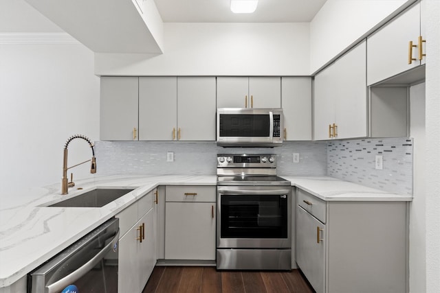 kitchen with dark wood finished floors, light stone countertops, stainless steel appliances, and a sink