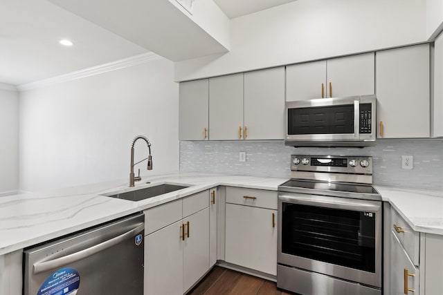 kitchen with dark wood-style floors, a sink, backsplash, ornamental molding, and appliances with stainless steel finishes