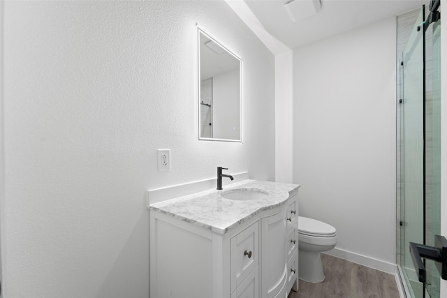 11534 Fernald Ave, Dallas, TX 75218 - full bathroom featuring wood finished floors, vanity, toilet, and a shower with door