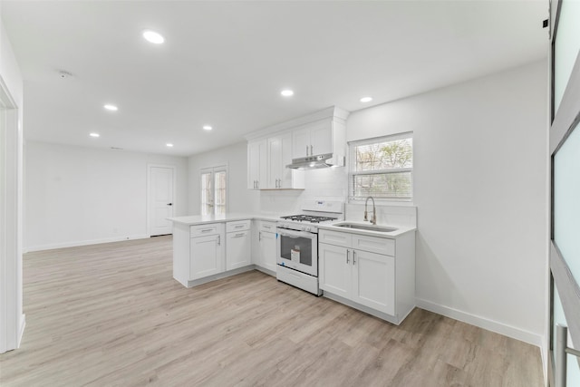 11534 Fernald Ave, Dallas, TX 75218 - kitchen with white range with gas cooktop, a peninsula, a sink, under cabinet range hood, and light wood-style flooring