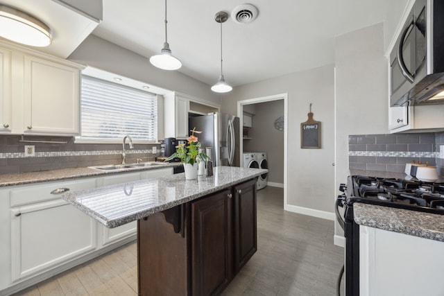 1225 Dumont Dr, Richardson, TX 75080 - kitchen with stainless steel appliances, washing machine and dryer, a sink, backsplash, and baseboards