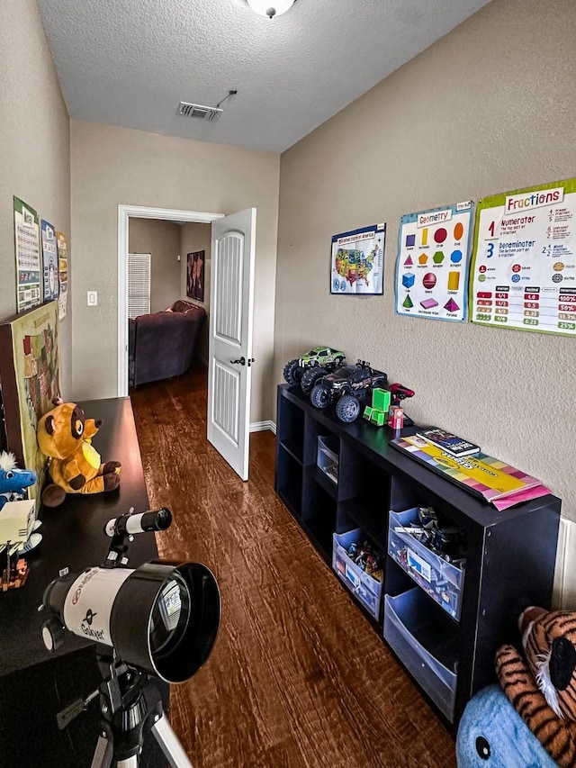 recreation room with wood finished floors and a textured ceiling