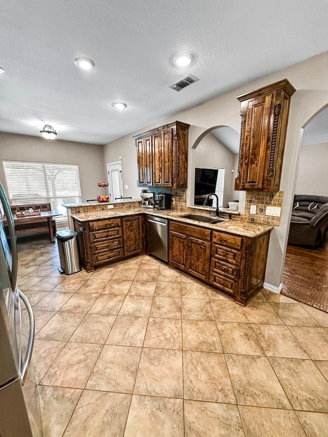 kitchen with arched walkways, stainless steel dishwasher, a sink, light tile patterned flooring, and recessed lighting