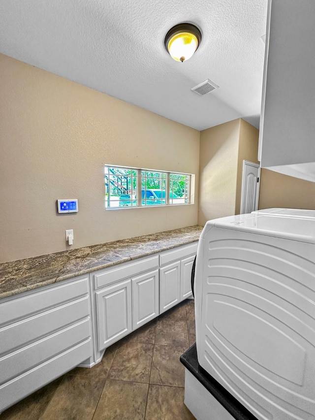 bedroom featuring a textured ceiling, washer / dryer, and dark tile patterned floors