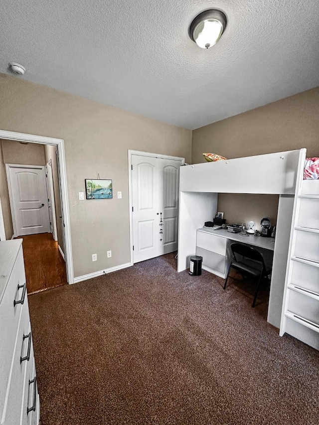 bedroom with dark colored carpet, a textured ceiling, and baseboards