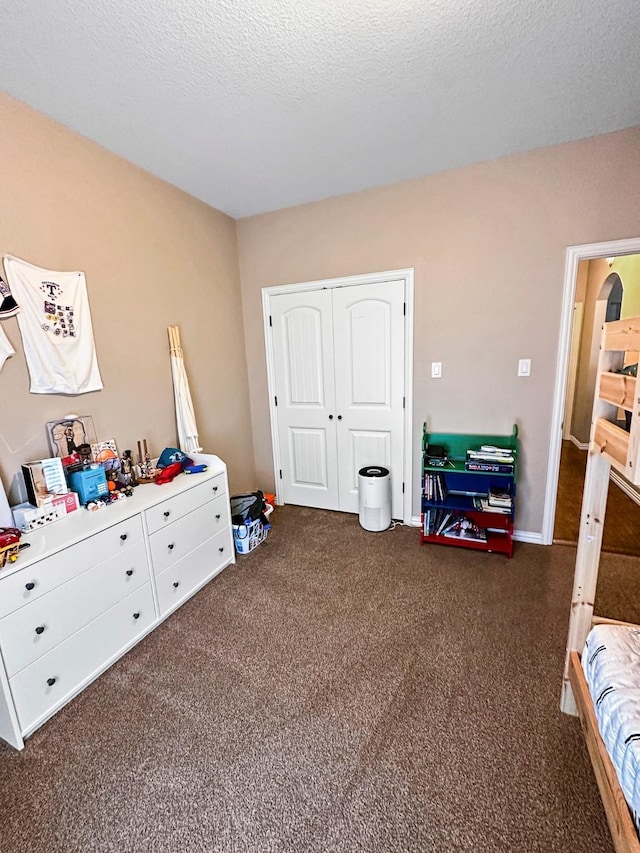 bedroom with dark carpet, a closet, and a textured ceiling