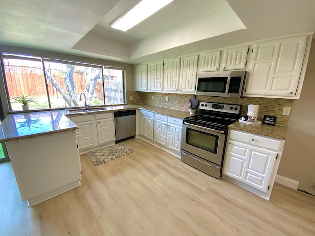 1332 Burmeister Rd, Fort Worth, TX 76134 - kitchen featuring decorative backsplash, light wood-style flooring, stainless steel appliances, a sink, and a tray ceiling