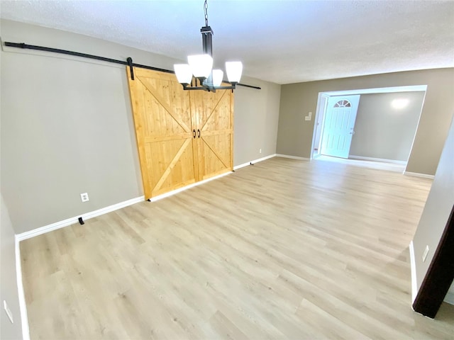 1332 Burmeister Rd, Fort Worth, TX 76134 - unfurnished room featuring an inviting chandelier, baseboards, a barn door, and light wood-type flooring
