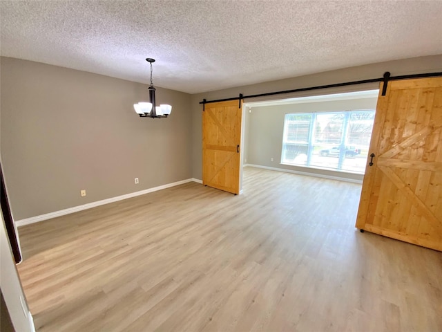 1332 Burmeister Rd, Fort Worth, TX 76134 - spare room featuring baseboards, a barn door, a chandelier, and light wood-type flooring