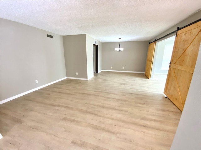 1332 Burmeister Rd, Fort Worth, TX 76134 - spare room featuring a barn door, a textured ceiling, visible vents, and light wood finished floors
