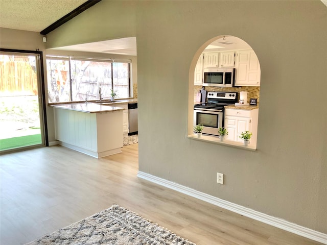 1332 Burmeister Rd, Fort Worth, TX 76134 - kitchen with backsplash, a peninsula, stainless steel appliances, plenty of natural light, and white cabinets