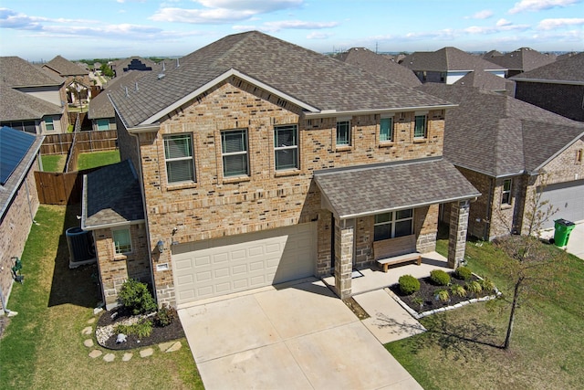 traditional-style home with an attached garage, roof with shingles, brick siding, and concrete driveway