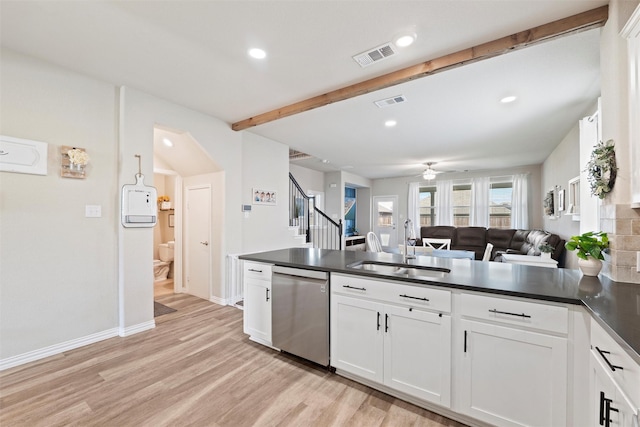 kitchen featuring stainless steel dishwasher, visible vents, dark countertops, a sink, and light wood finished floors