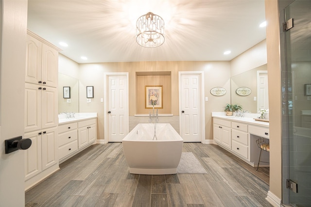 1022 High Meadow Dr, Mount Vernon, TX 75457 - full bathroom with a chandelier, wood finished floors, a freestanding tub, two vanities, and a stall shower