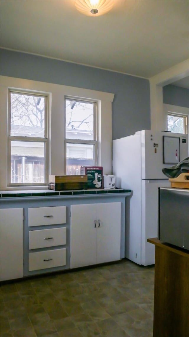 kitchen featuring white cabinetry and freestanding refrigerator