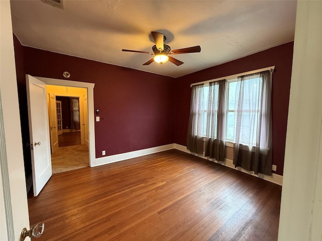 empty room featuring wood finished floors, ceiling fan, and baseboards