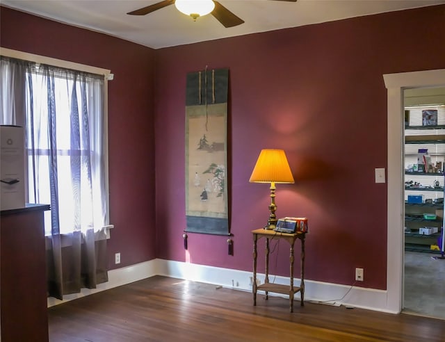 interior space with a ceiling fan, wood finished floors, and baseboards