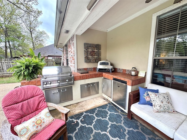 view of patio featuring an outdoor kitchen, visible vents, a grill, and fence