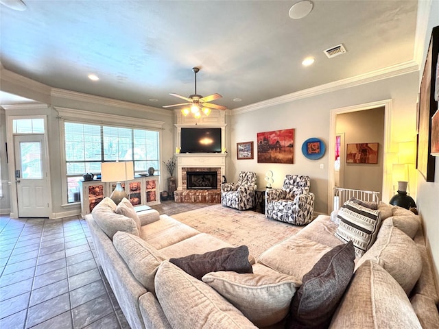 tiled living area with crown molding, visible vents, ceiling fan, and a fireplace with raised hearth