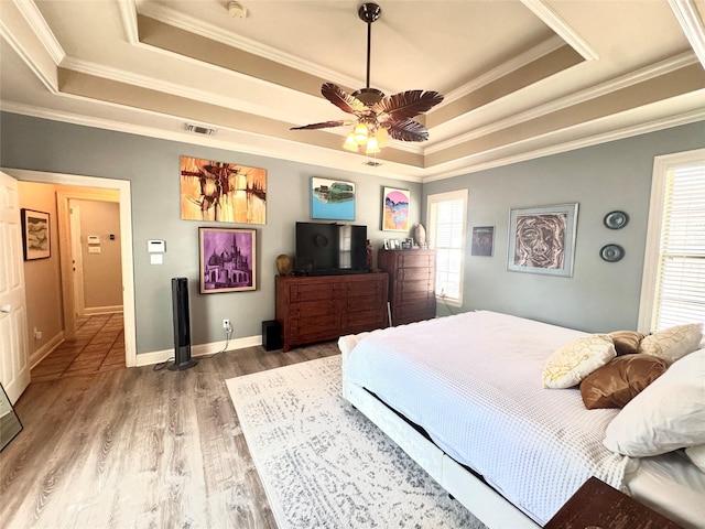 bedroom featuring crown molding, a ceiling fan, visible vents, a raised ceiling, and wood finished floors