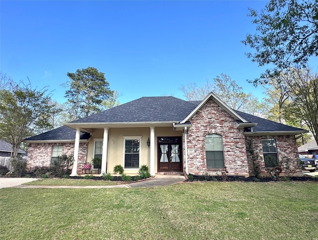 view of front of home with stucco siding, brick siding, french doors, a front lawn, and roof with shingles