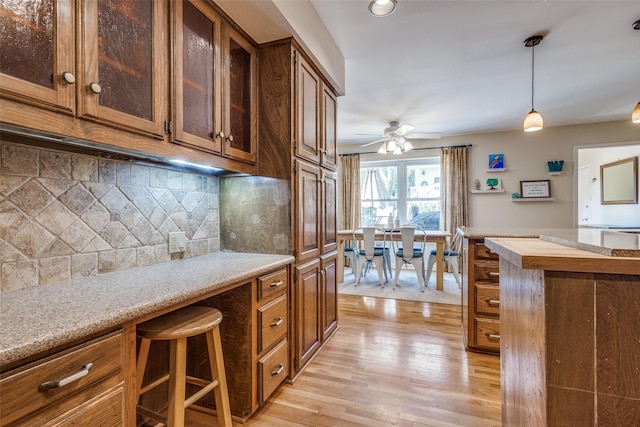 328 S Jackson Ave, Justin, TX 76247 - kitchen with light wood-type flooring, a ceiling fan, decorative light fixtures, tasteful backsplash, and glass insert cabinets