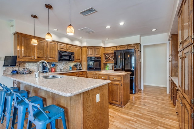328 S Jackson Ave, Justin, TX 76247 - kitchen featuring black appliances, a sink, a peninsula, brown cabinetry, and light wood-style flooring
