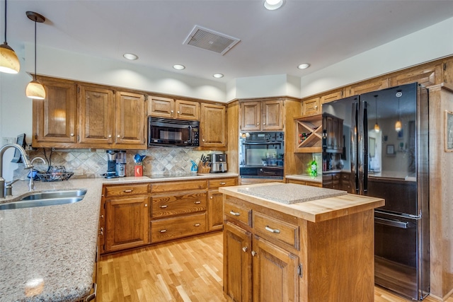 328 S Jackson Ave, Justin, TX 76247 - kitchen with black appliances, a sink, light wood finished floors, hanging light fixtures, and butcher block counters