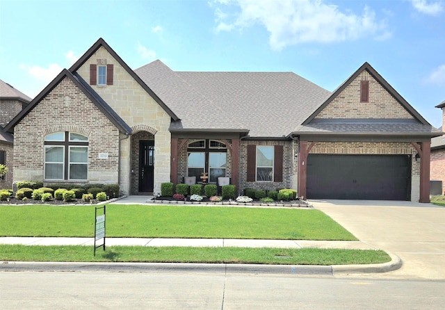 1214 Norwood St, Mansfield, TX 76063 - french country inspired facade with an attached garage, a front lawn, stone siding, brick siding, and concrete driveway