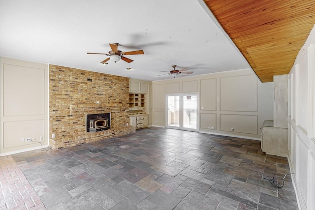 102 Cedar Dr, Oak Leaf, TX 75154 - unfurnished living room with a wood stove, wood ceiling, ceiling fan, a decorative wall, and stone tile flooring