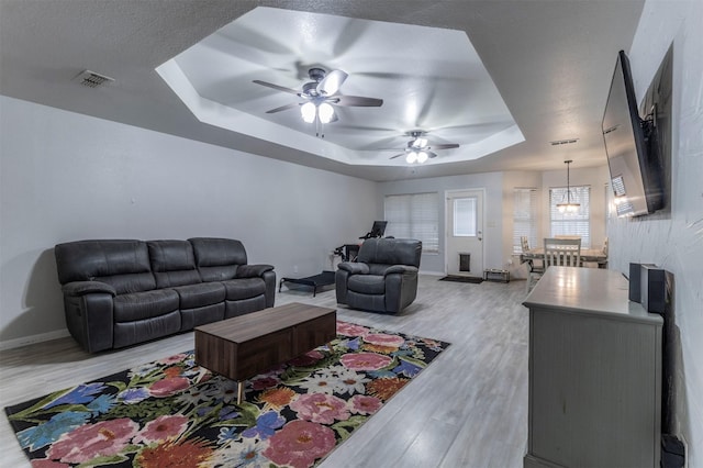 509 Brockett St, Aubrey, TX 76227 - living room featuring a raised ceiling, light wood-type flooring, ceiling fan, baseboards, and a chandelier