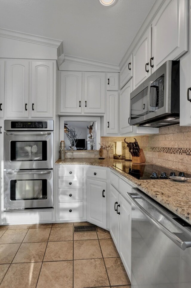 4901 Fairway Ct, De Cordova, TX 76049 - kitchen featuring light tile patterned flooring, tasteful backsplash, appliances with stainless steel finishes, white cabinets, and ornamental molding