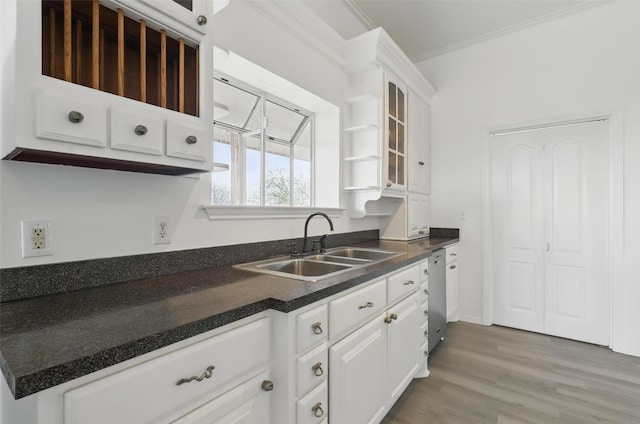 kitchen with ornamental molding, dark countertops, glass insert cabinets, white cabinetry, and a sink