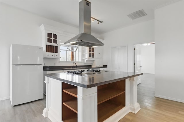 kitchen with island exhaust hood, visible vents, freestanding refrigerator, and open shelves