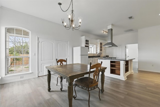 dining area featuring baseboards, visible vents, wood finished floors, and a chandelier