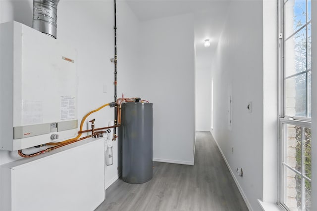 interior space featuring water heater, tankless water heater, baseboards, and light wood-type flooring