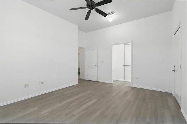 unfurnished bedroom with a closet, visible vents, baseboards, ceiling fan, and wood finished floors