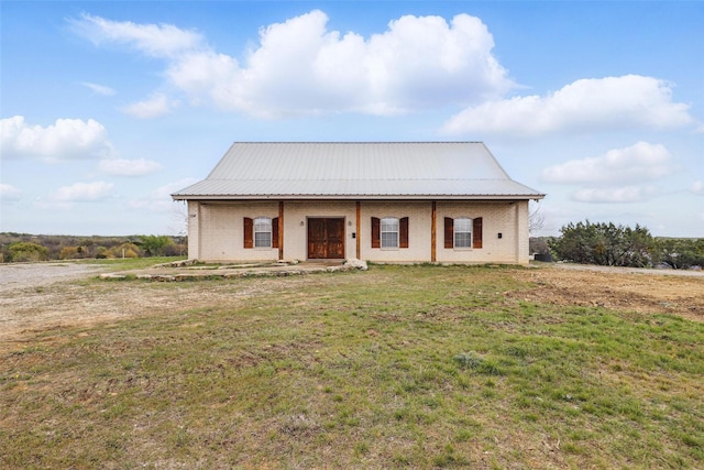 view of front of house with brick siding, a front lawn, and metal roof