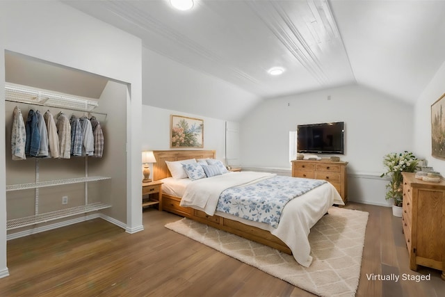 bedroom featuring baseboards, vaulted ceiling, and wood finished floors