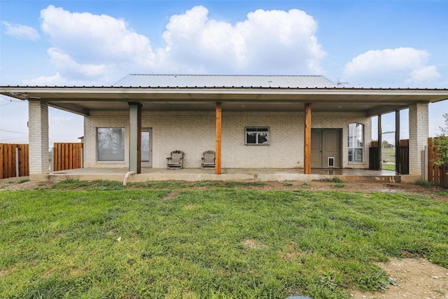back of property featuring a yard, brick siding, and fence