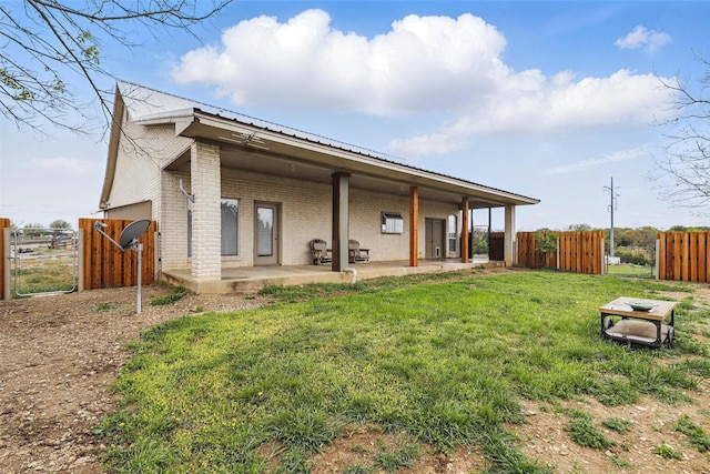 rear view of house featuring a yard, brick siding, fence, and a patio