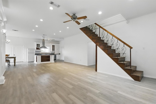 living area with light wood finished floors, stairs, visible vents, and ceiling fan