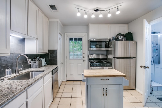 kitchen featuring butcher block countertops, visible vents, appliances with stainless steel finishes, a sink, and light tile patterned floors