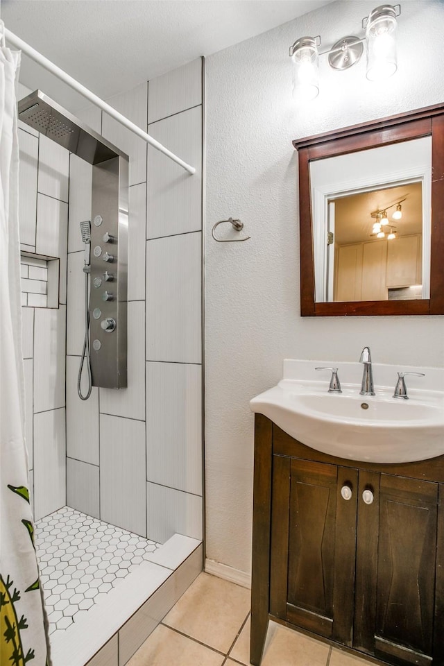 full bathroom featuring tile patterned flooring, vanity, and a tile shower