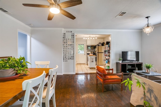 dining room with hardwood / wood-style flooring, crown molding, and visible vents
