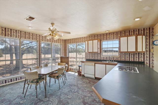 interior space featuring wallpapered walls, a textured ceiling, ceiling fan, and visible vents