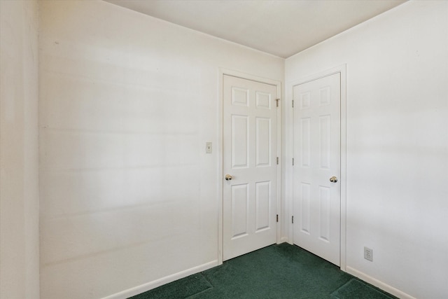unfurnished room with baseboards and dark colored carpet