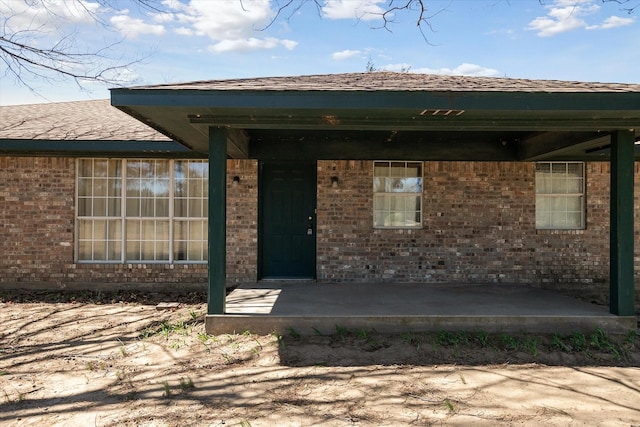 property entrance with brick siding and a shingled roof