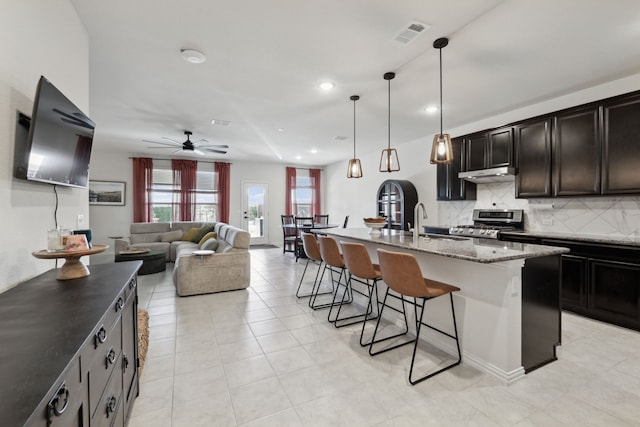 342 Meredith Dr, Fate, TX 75087 - kitchen with a kitchen bar, stainless steel range, backsplash, dark stone counters, and a ceiling fan